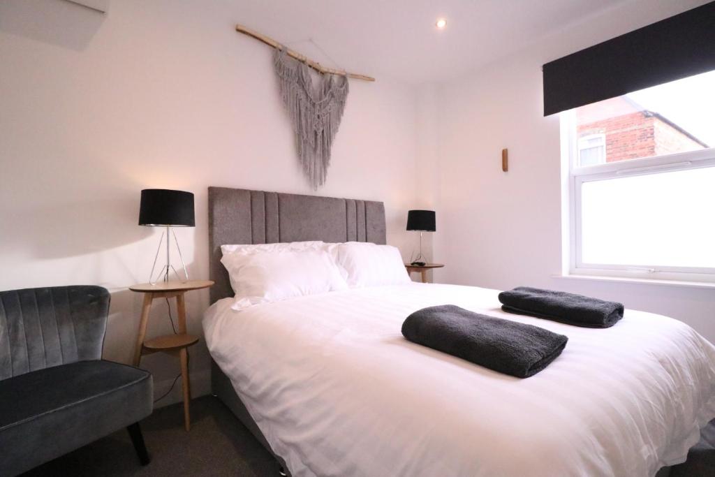 ein Schlafzimmer mit einem weißen Bett mit einem Stuhl und einem Fenster in der Unterkunft Amaya Six - Beautifully renovated with the latest tech & FAST Wi-Fi in Grantham