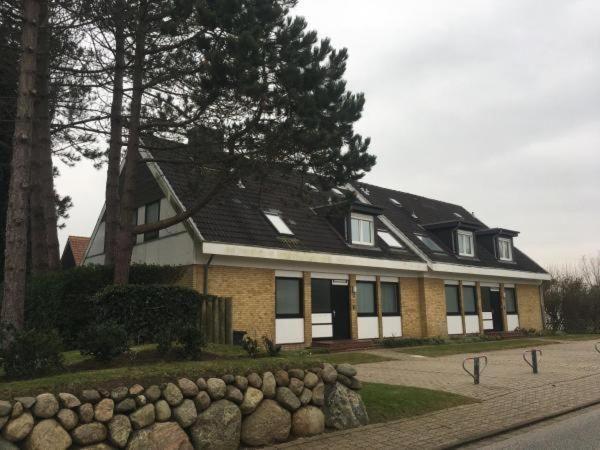 uma casa com um telhado preto e uma parede de pedra em Ferienwohnung-Kolberger em Westerland