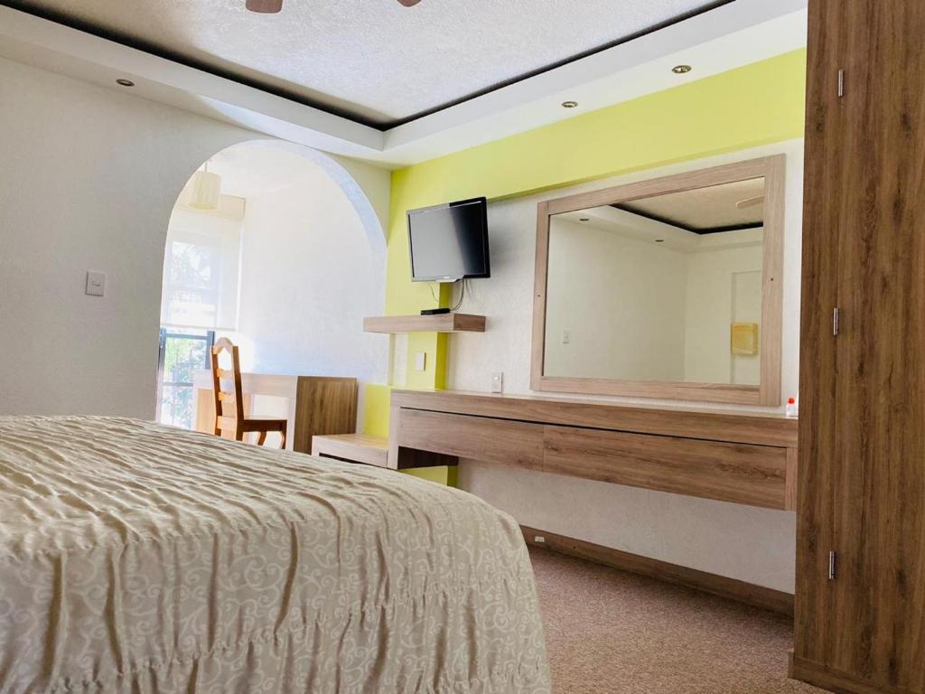1 dormitorio con espejo grande y cama en Hotel La Mansión, en San José Iturbide