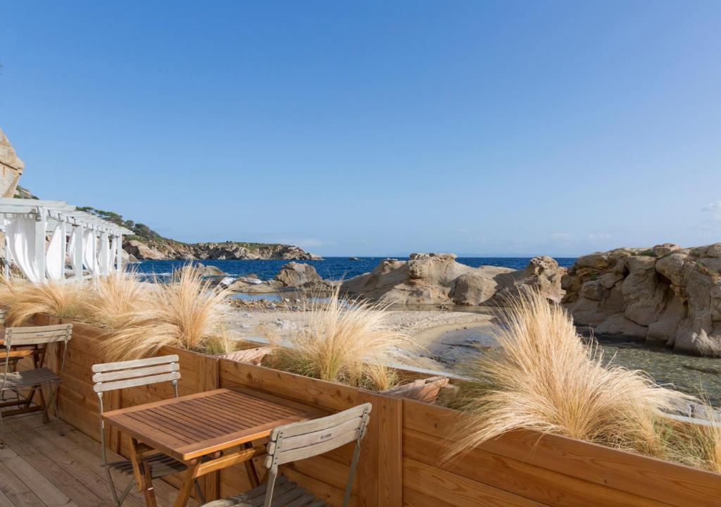 a patio with a wooden table and chairs and the ocean at LA GUARDIA Hotel in Giglio Porto