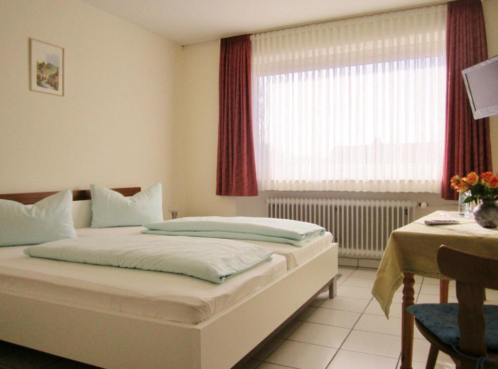 a bedroom with a bed and a table and a window at Hotel Jägersruh in Monschau