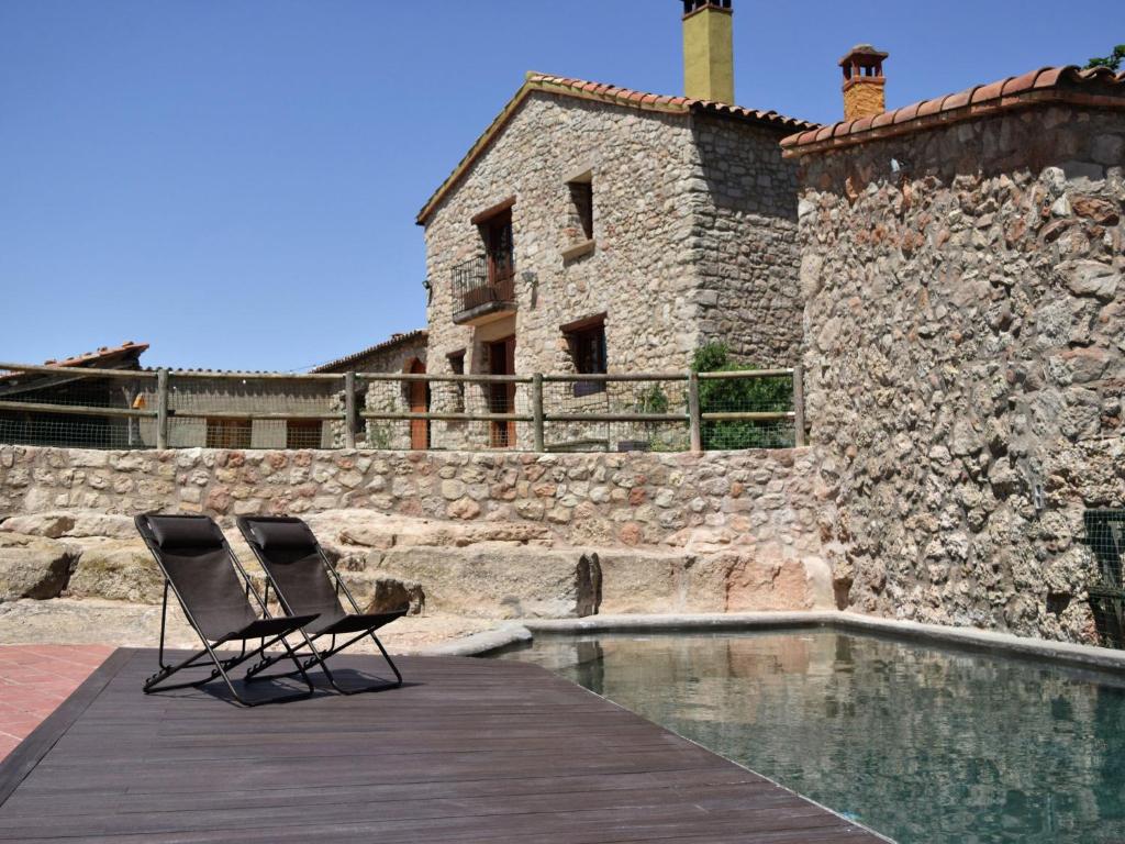Castellolí的住宿－Belvilla by OYO Cal Sant Miquel，游泳池旁的甲板上摆放着两把椅子