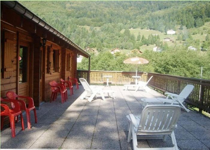 eine Terrasse mit Stühlen, Tischen und einem Sonnenschirm in der Unterkunft Hotel Restaurant Home Des Hautes Vosges in La Bresse