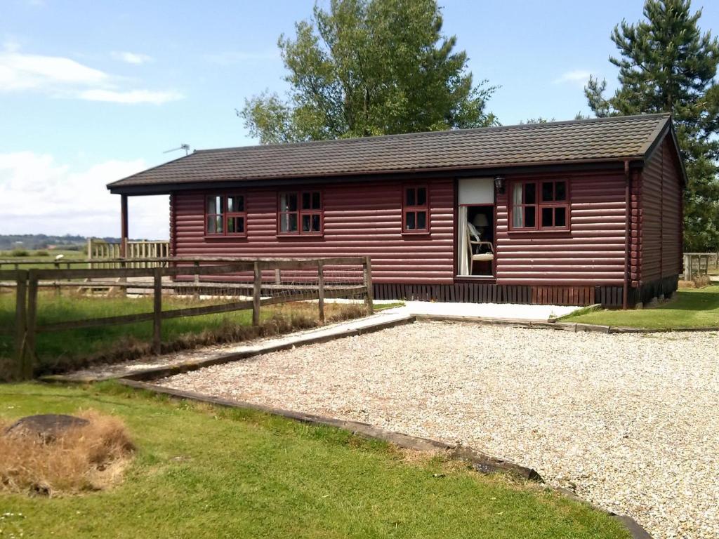 a small red house with a gravel yard in front of it at Modern Cottage in Romney Marsh near Lake in Brookland