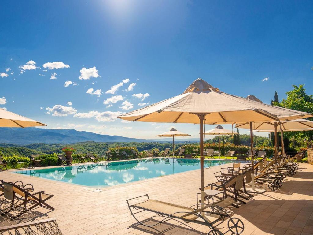 einen Pool mit Stühlen und Sonnenschirmen in der Unterkunft Belvilla by OYO Gaville 8 in Figline Valdarno