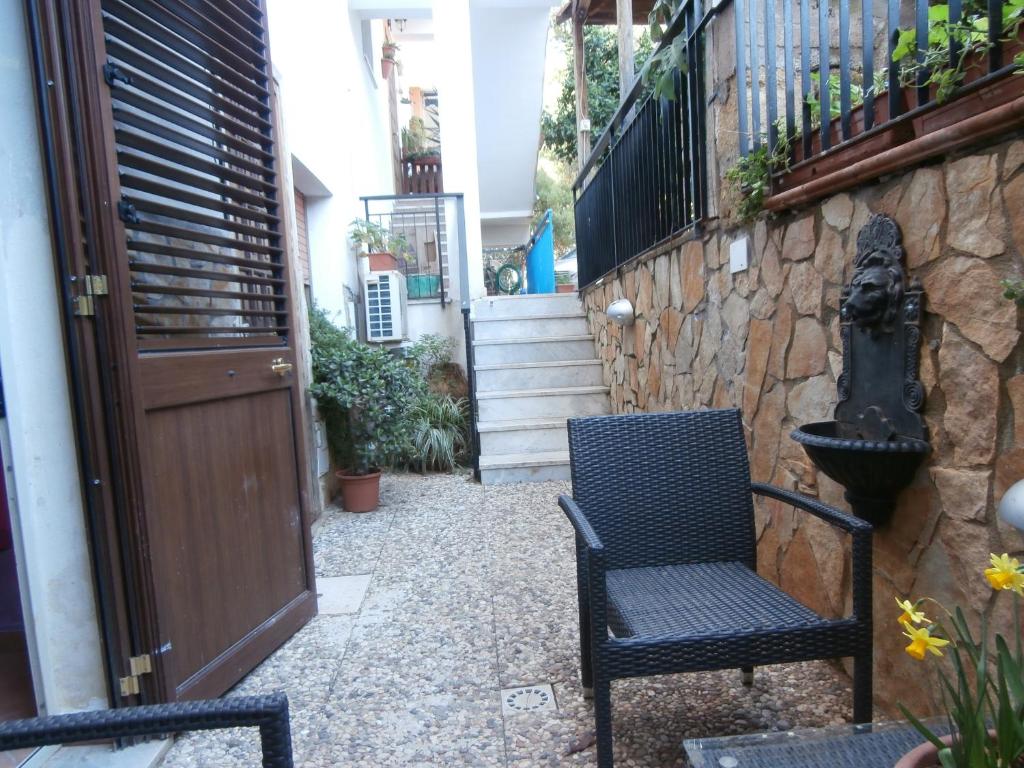 a patio with two chairs next to a stone wall at Busalacchi B&B in Mondello