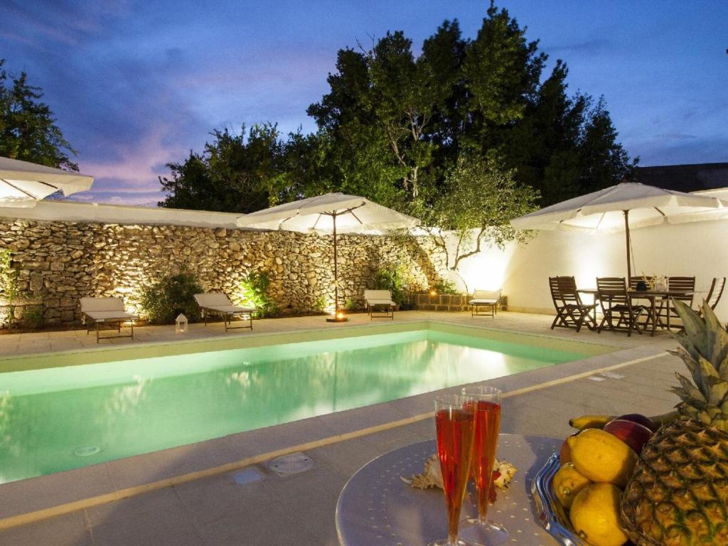 uma piscina com uma mesa com fruta ao lado em Villa consisting of 5 apartments with swimming pool, near center, sea 6 km em Racale