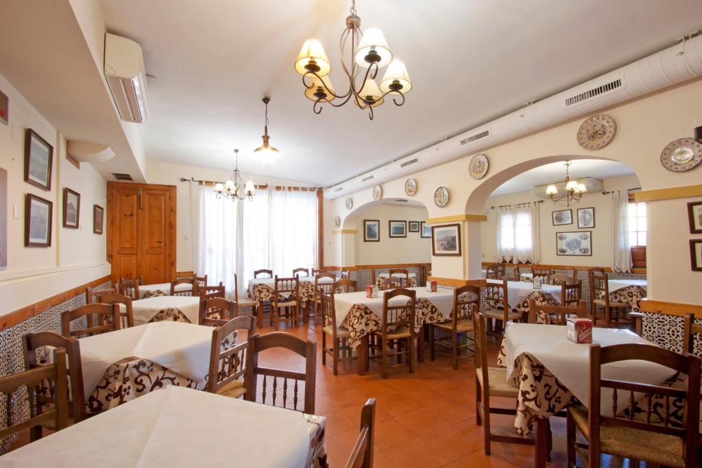 a restaurant with tables and chairs and a chandelier at Hostal El Cortijo in Algodonales