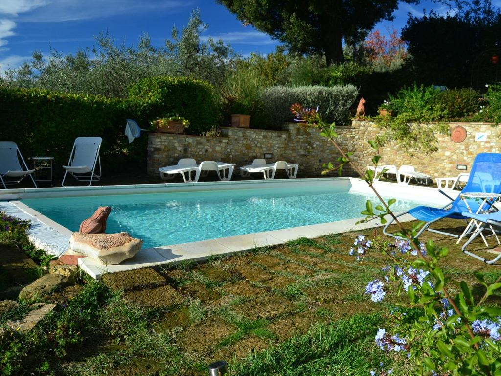 タヴァルネッレ・ヴァル・ディ・ペーザにあるCozy Holiday Home in Tavarnelle Val di Pesa with Shared Poolの椅子と芝生のある庭のスイミングプール