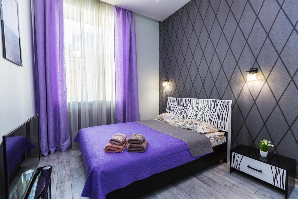 una camera da letto con tende viola e un letto con pantofole di 8 Svyatoho Teodora Square Apartments a Lviv
