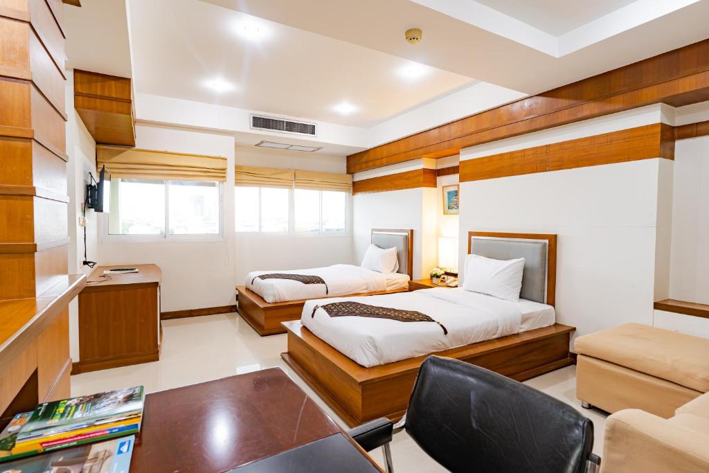 una camera con 2 letti, una scrivania e una sedia di Sirin Hotel & Resident a Khon Kaen