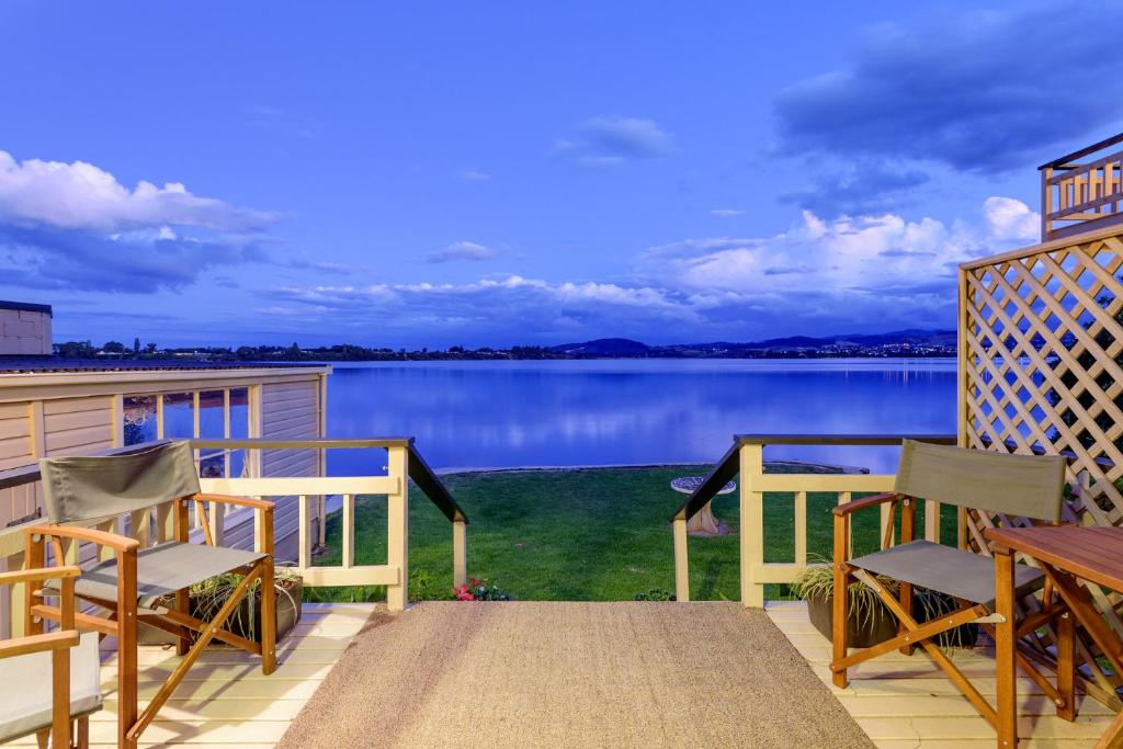 タウランガにあるStay Coastal - Tauranga Beach Houseのポーチ(椅子付)が備わり、水辺の景色を望めます。