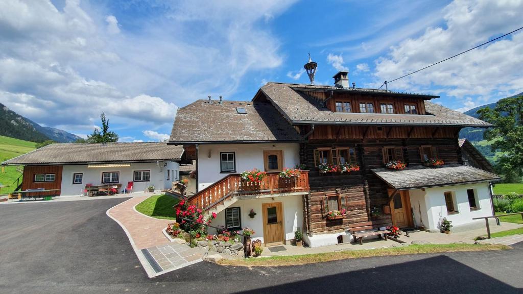 een groot houten huis met bloemen ervoor bij Schmiedlehnerhof in Birnberg