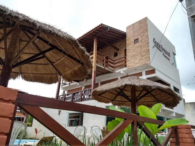 un edificio con dos sombrillas delante en Pousada Costa Tropical en Tamandaré