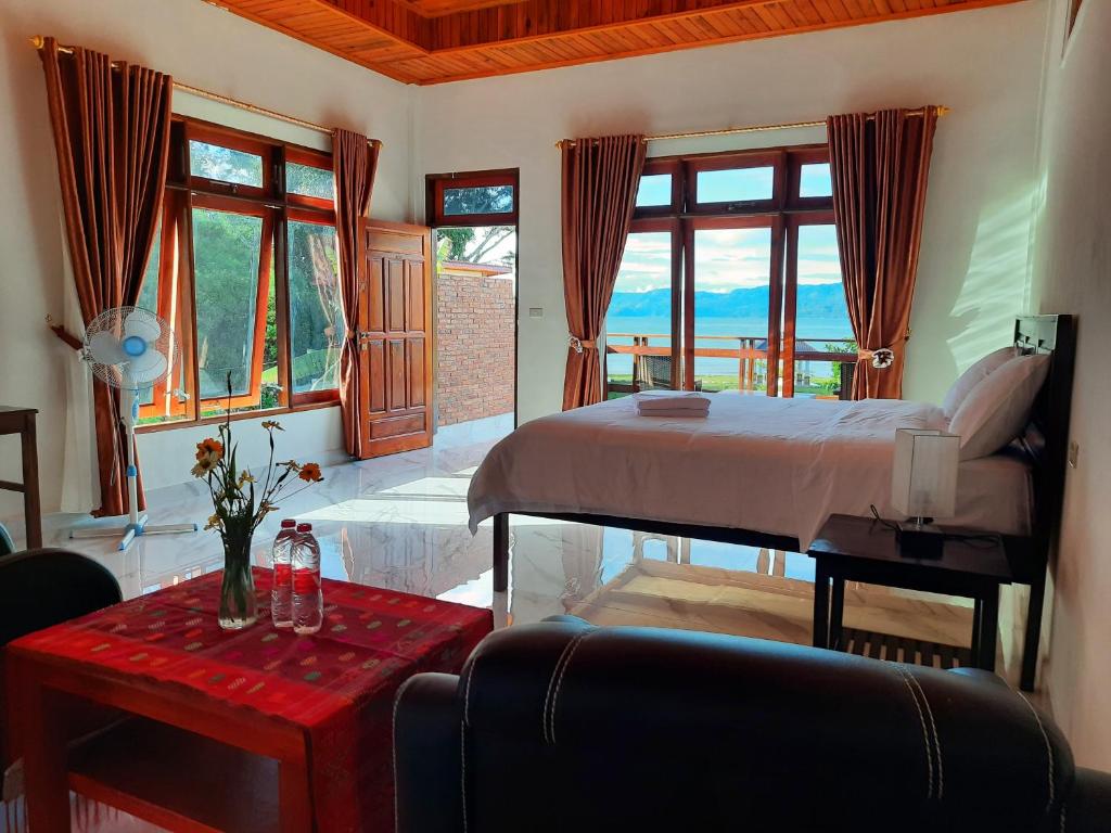 una camera con letto, tavolo e finestre di Juma cottages a Tuk Tuk