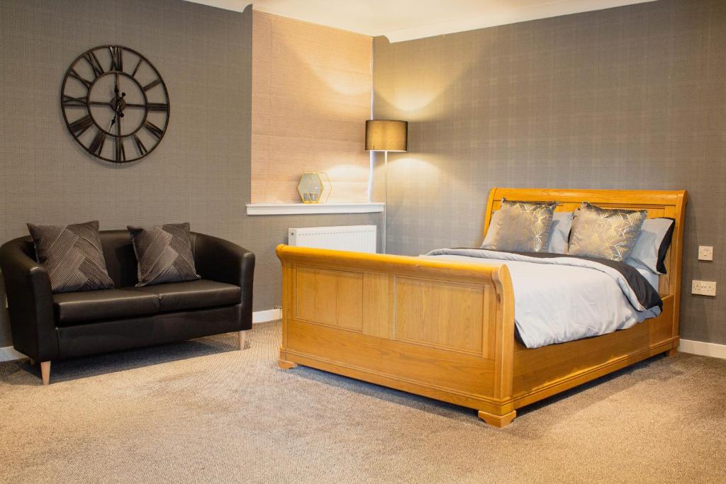 una camera con letto, sedia e orologio di Forth Apartments a Kirkcaldy