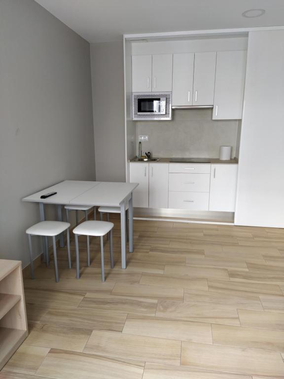 cocina con armarios blancos, mesa y sillas en APARTAMENTO SENDA SUR, en Porriño