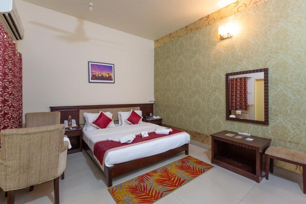 a hotel room with a bed and a table and a chair at KSTDC Mayura Durg Chitradurga in Chitradurga