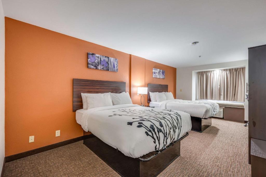 two beds in a hotel room with orange walls at Sleep Inn & Suites in Decatur