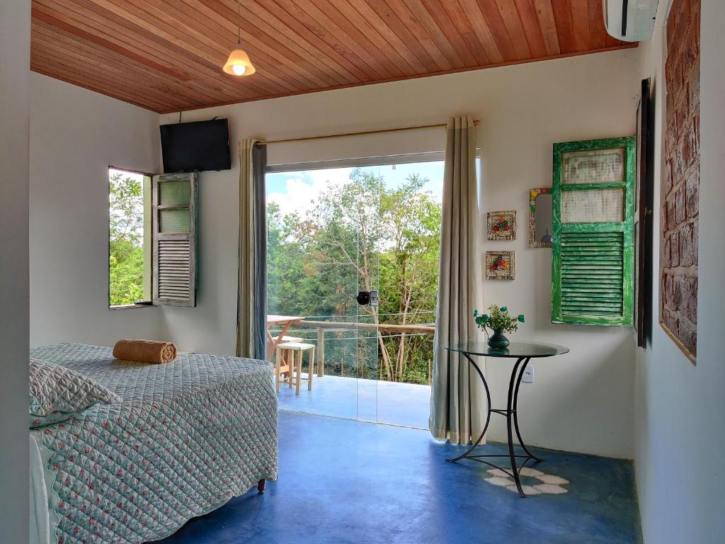 a bedroom with a bed and a table and a balcony at Lençóis Apartamento Suíte Master Green in Lençóis