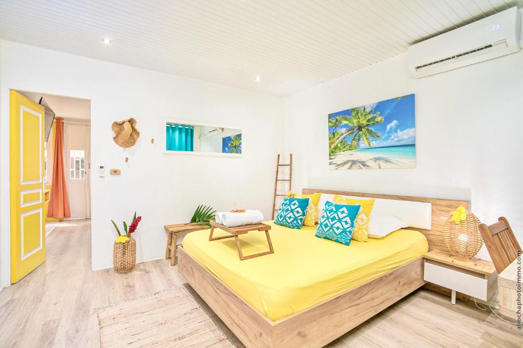 a bedroom with a bed with yellow sheets and blue pillows at Foyal Suites in Fort-de-France