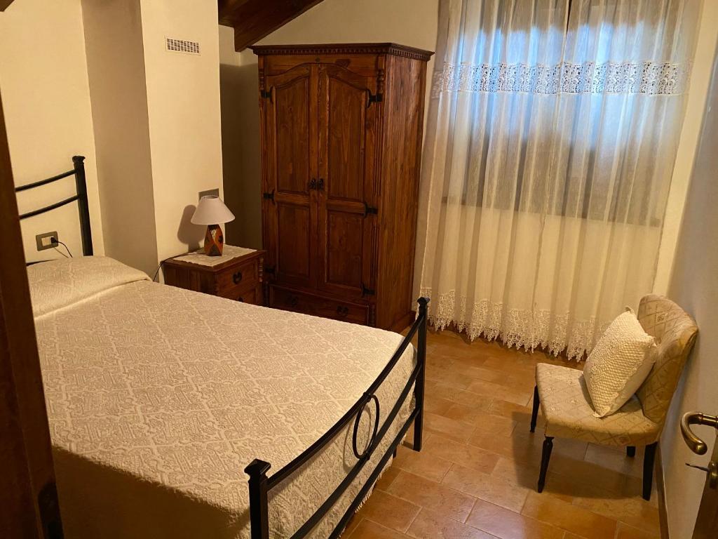sypialnia z łóżkiem, krzesłem i oknem w obiekcie Agriturismo il canale w mieście Corfino