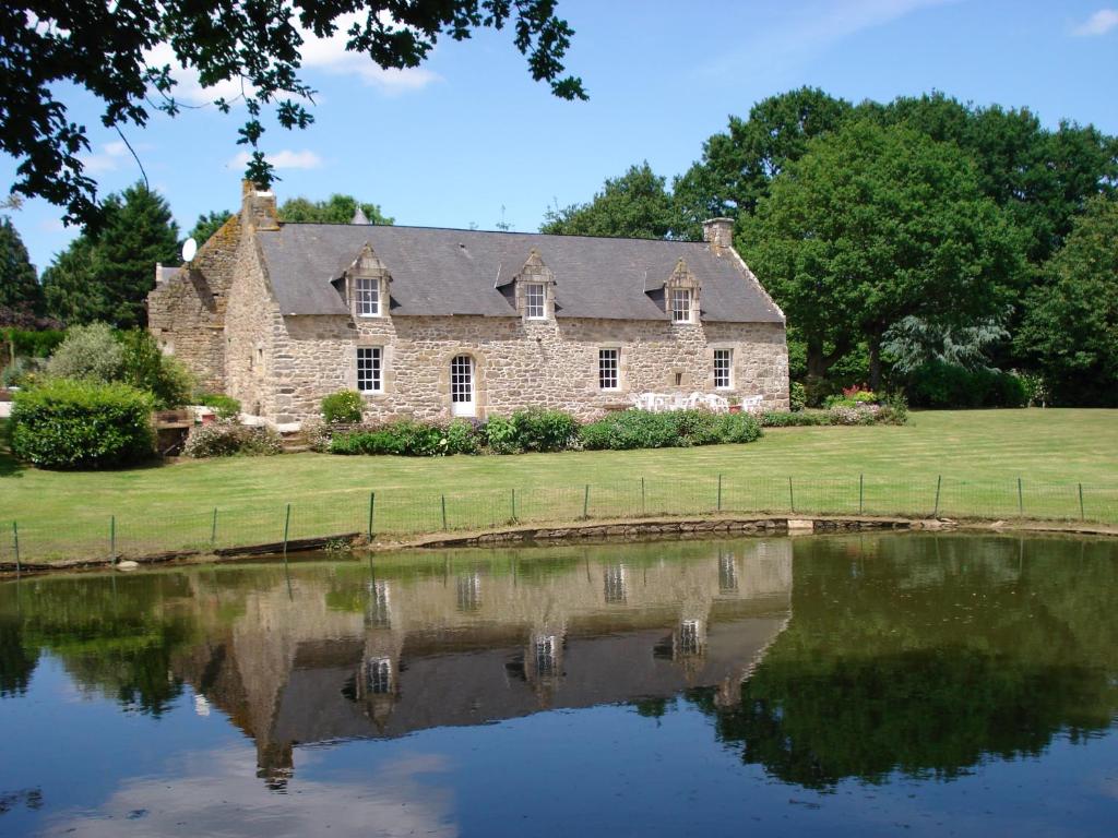 una vieja casa de piedra con un estanque delante de ella en Gite de Cohignac, en Berric