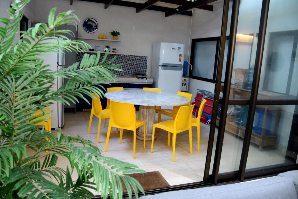 a dining room with a table and yellow chairs at BARRA BALI 04 quartos Barra de São Miguel in Barra de São Miguel