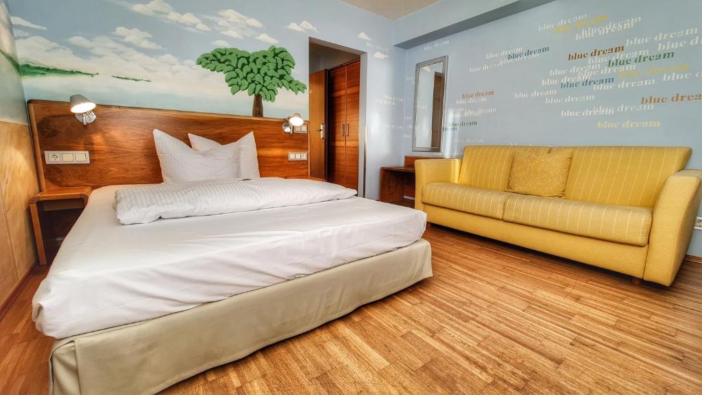 een slaapkamer met een bed en een gele bank bij Hotel Restaurant Felix in Bensheim