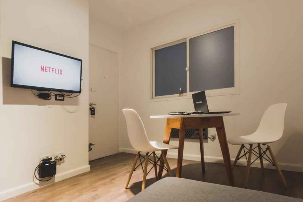 Habitación con escritorio con monitor y sillas blancas. en A Metros del Parana, en Rosario