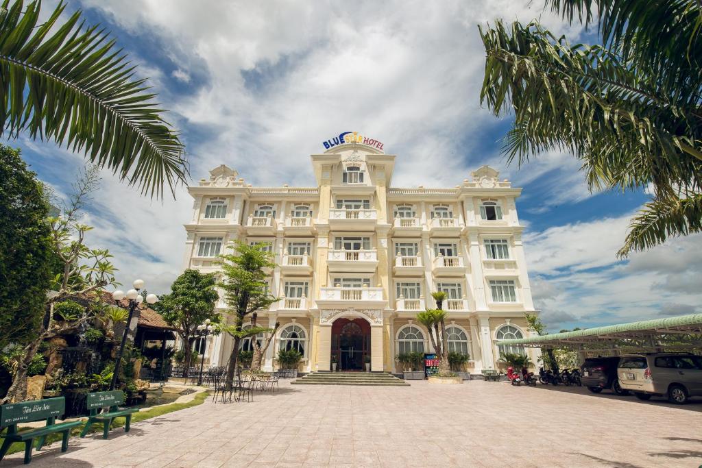 BLUE STAR HOTEL في Tây Ninh: مبنى أبيض كبير على شارع مرصوف بالحصى