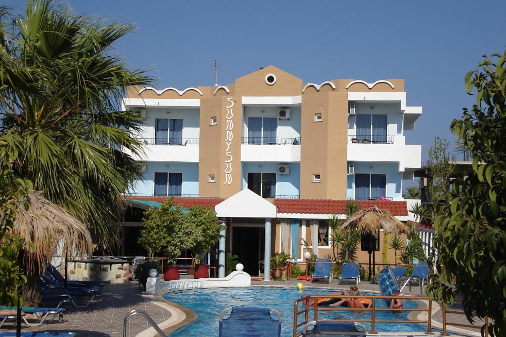 a hotel with a swimming pool in front of a building at SunnySun Studios in Faliraki