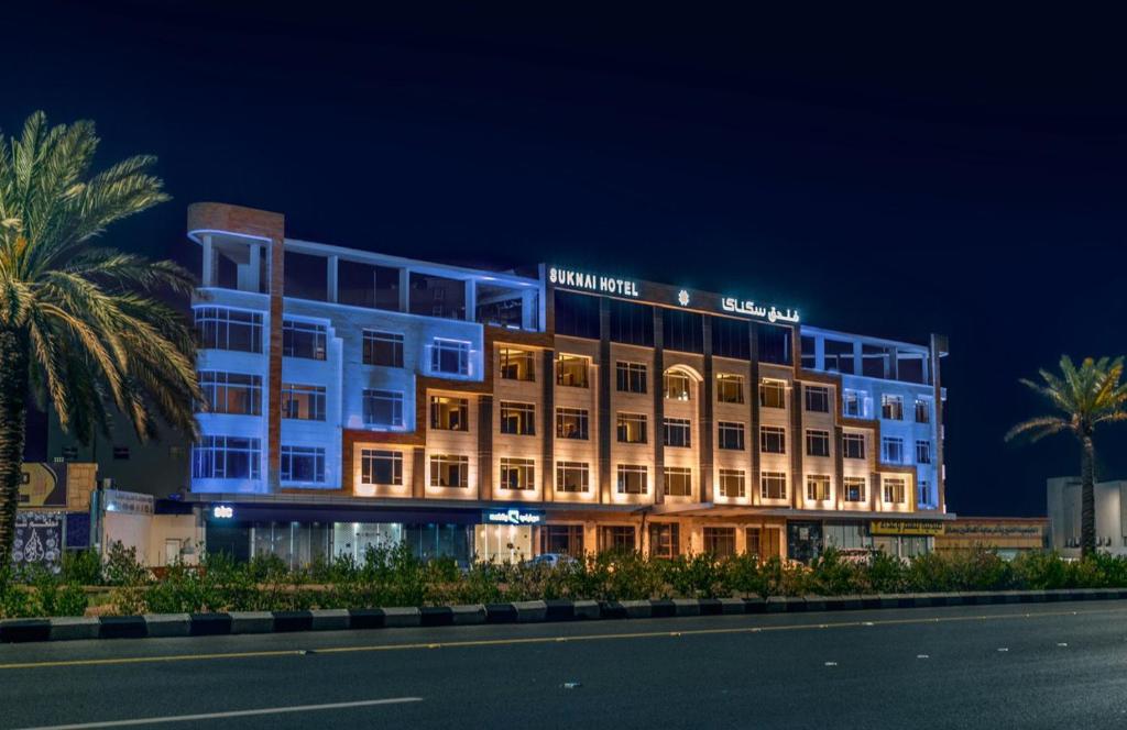einem beleuchteten Gebäude mit Palmen davor in der Unterkunft Suknai Royal Hotel in Ha'il