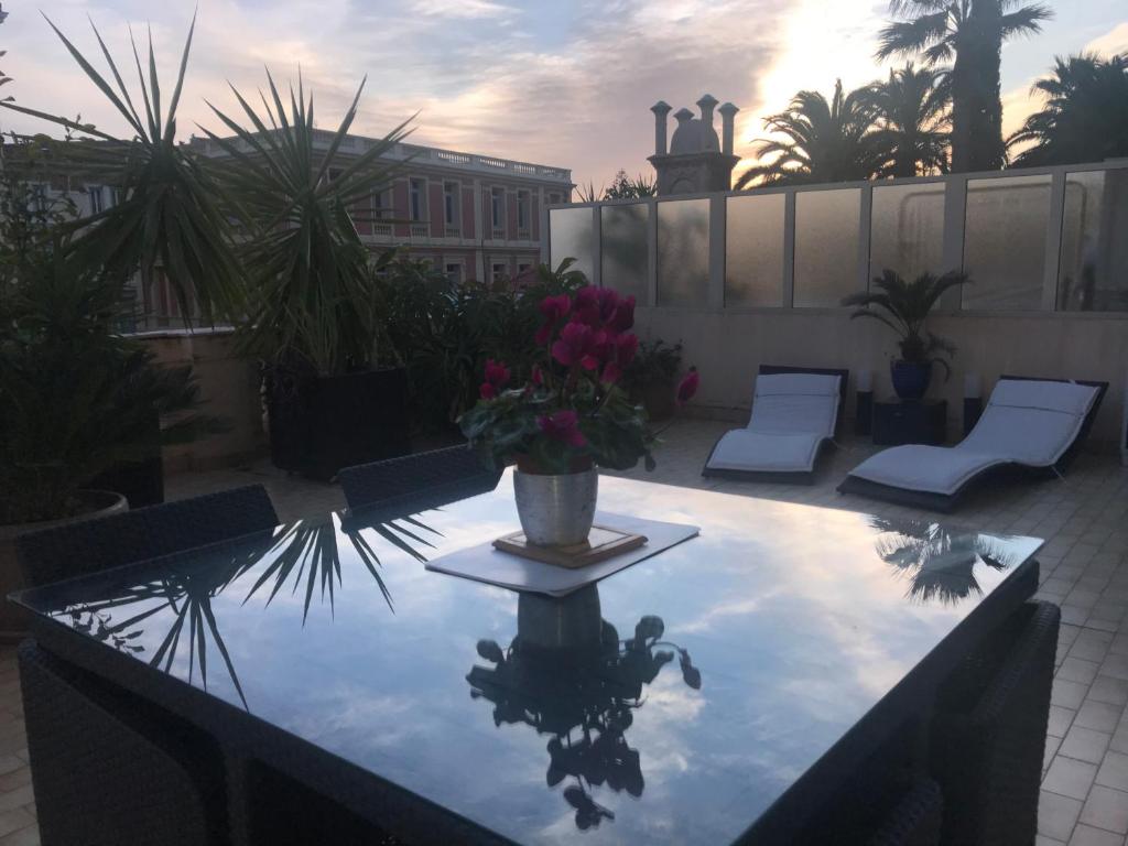 une terrasse avec une table et un vase de fleurs. dans l'établissement Appartement Terrasse dans Palace Centre ville, à Menton