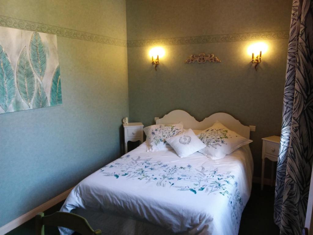 una camera da letto con letto, lenzuola e cuscini bianchi di LE MOULIN DE MERAL a Montsûrs