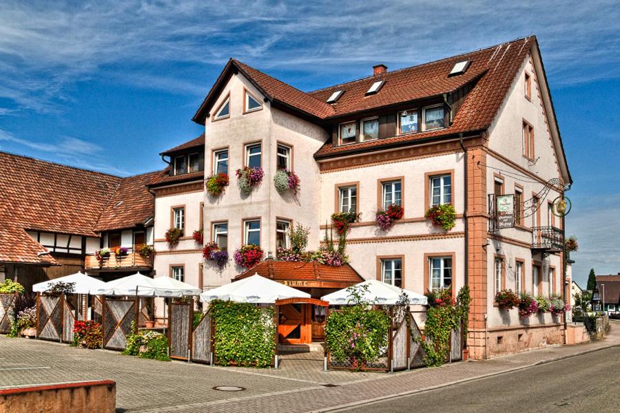 ein großes weißes Gebäude mit Sonnenschirmen davor in der Unterkunft Gasthaus Blume in Willstätt