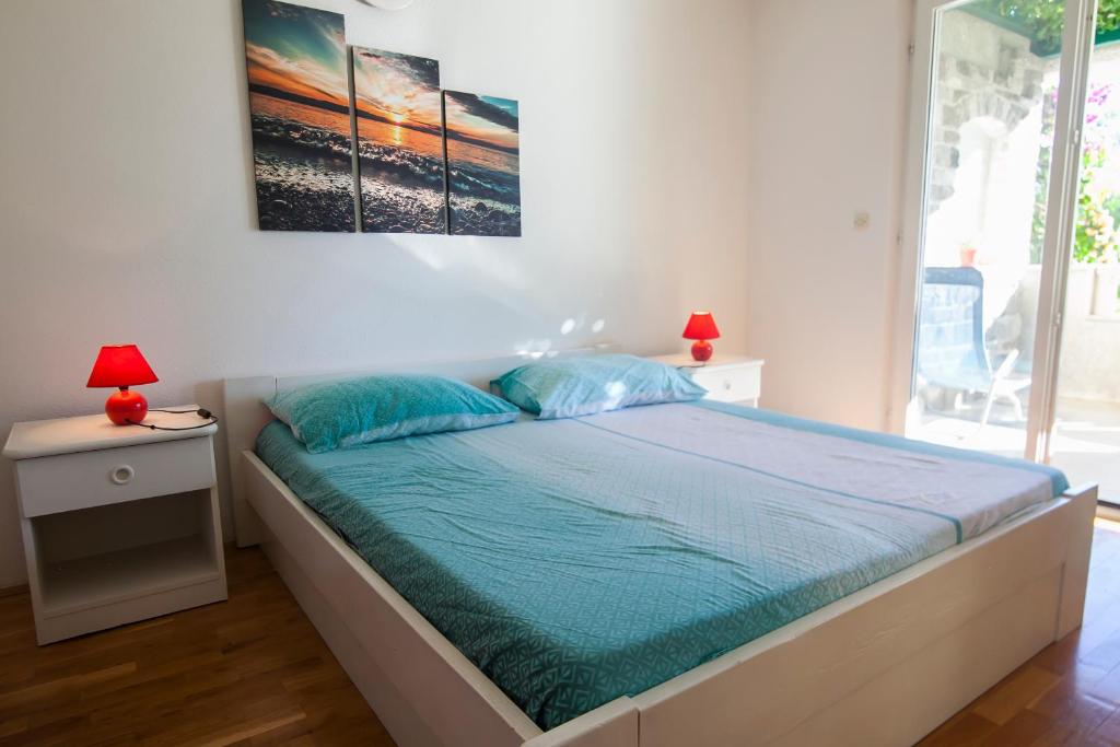 a bedroom with a bed with blue pillows and two lamps at Apartments Radić in Bol