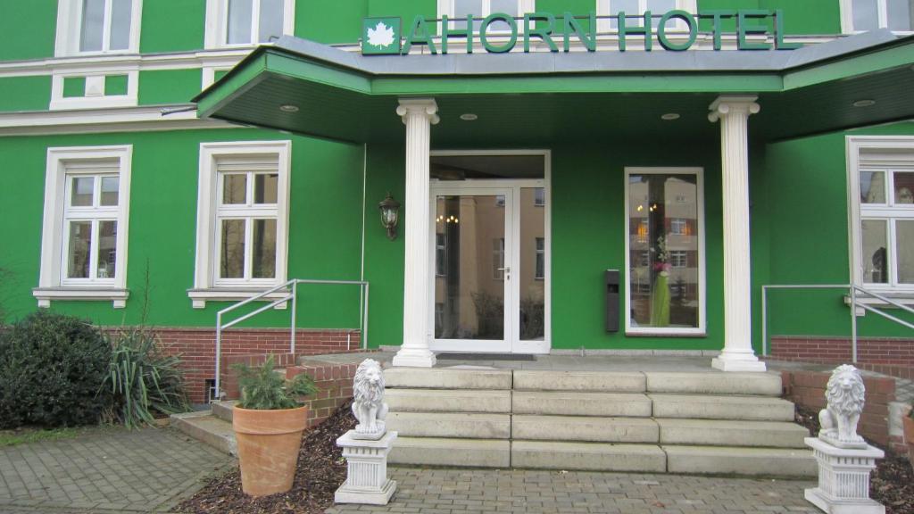 a green building with stairs in front of it at Ahorn Hotel in Cottbus