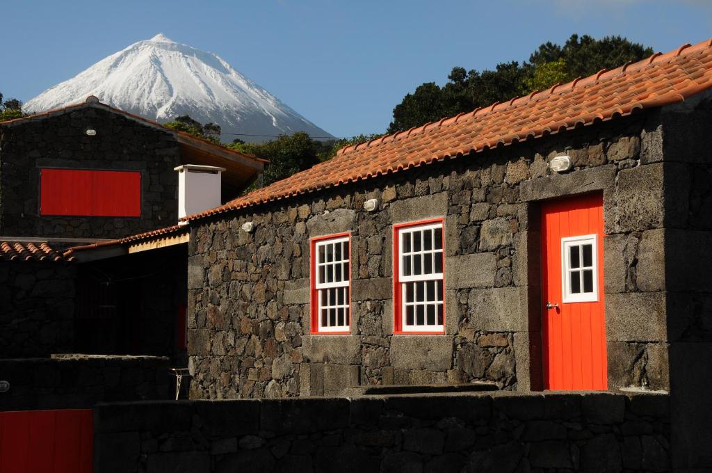 un edificio con una puerta roja y una montaña cubierta de nieve en Casas das Portas do Mar e das Portas do Sol, en São Roque do Pico