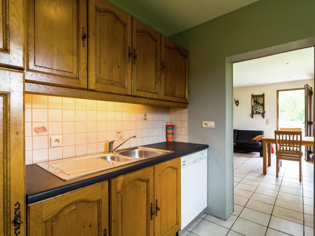 a kitchen with wooden cabinets and a sink at Perfect spot on the edge of a large wood in Awenne