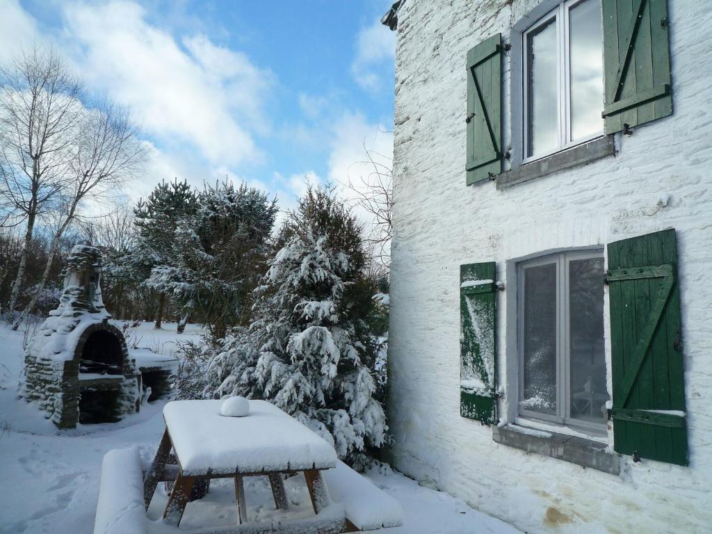 un banco cubierto de nieve frente a una casa en Beautiful and authentic cottage in the heart of the Ardennes, en Houffalize