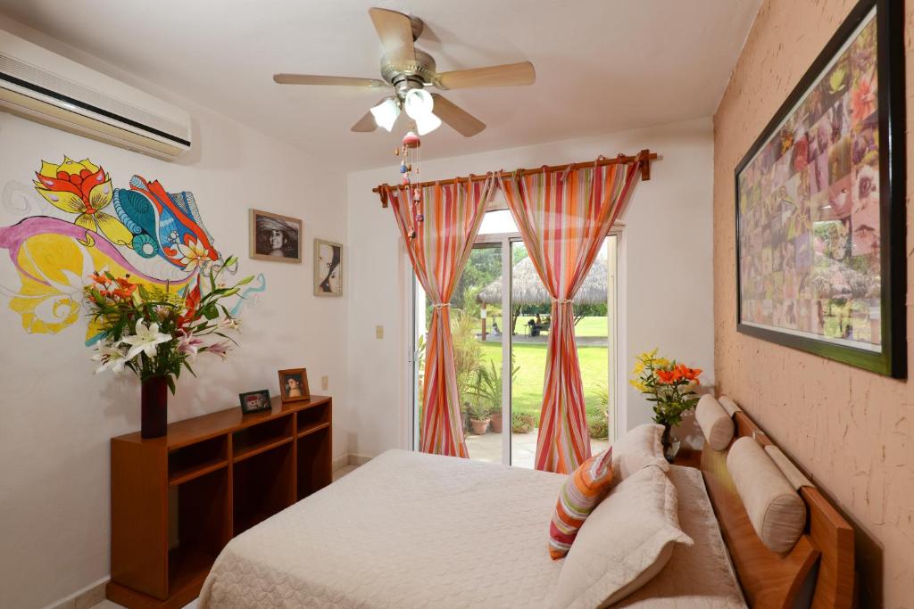 a bedroom with a bed with a ceiling fan and a window at B&B Mom's House in Puerto Aventuras