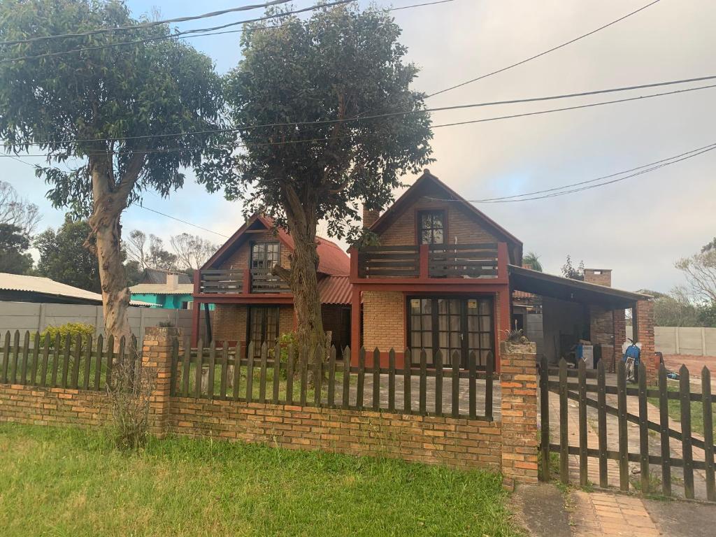une maison avec une clôture devant elle dans l'établissement Cabañas Barra Linda, à Barra del Chuy