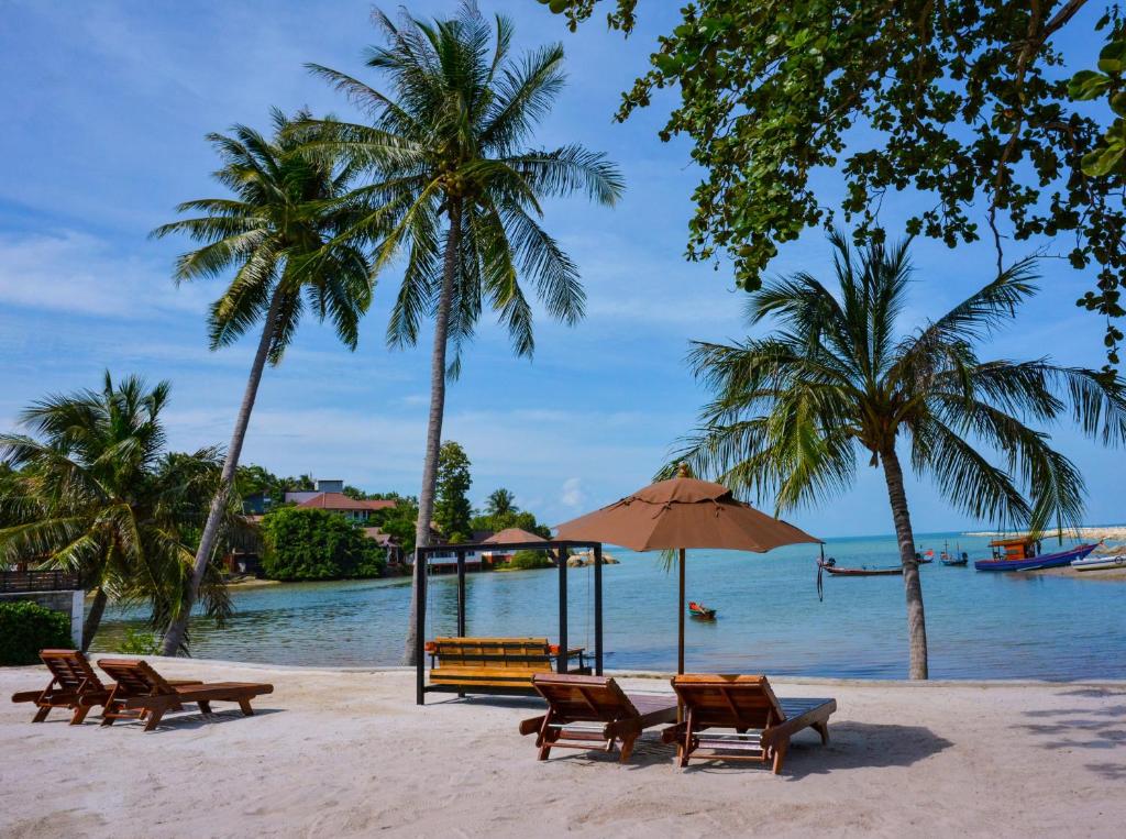 einen Strand mit Stühlen, einem Sonnenschirm und Palmen in der Unterkunft DANUP VILLA in Wok Tum