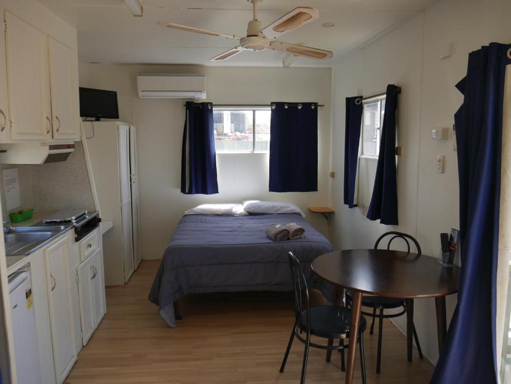 a small bedroom with a bed and a table at Parkes Country Cabins in Parkes