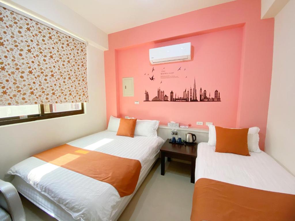 Duas camas num quarto com paredes cor-de-rosa em Yang's B&B em Jinning