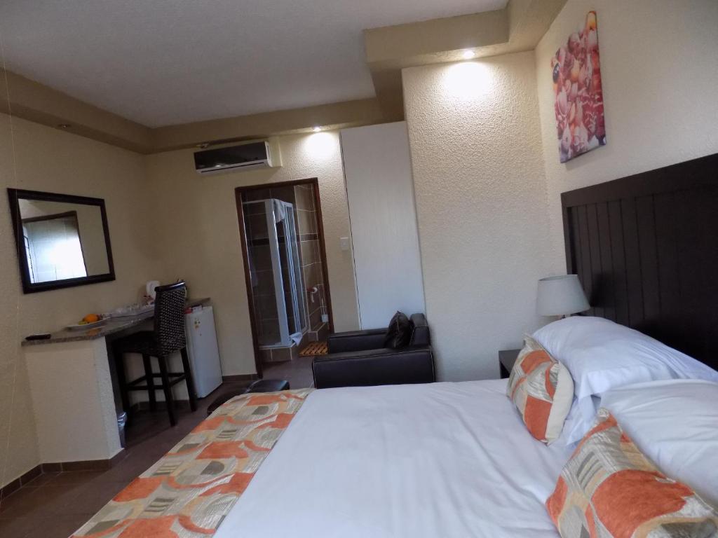 1 dormitorio con 1 cama blanca grande y escritorio en Margate Beach Lodge en Margate