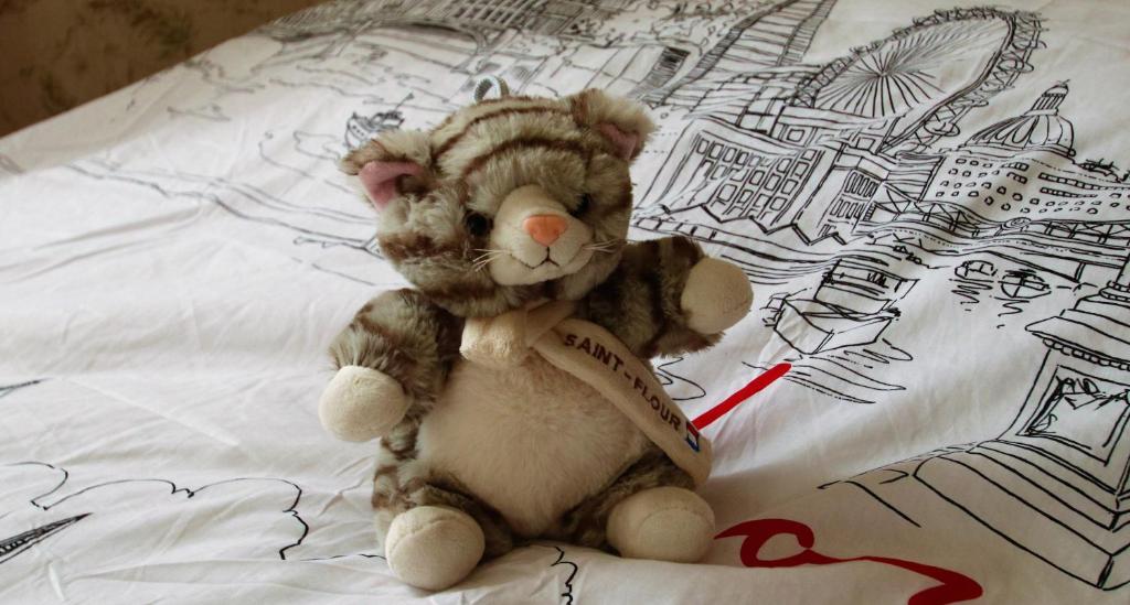 a stuffed teddy bear sitting on a bed at La Maison des Chats in Saint-Mary-le-Plain