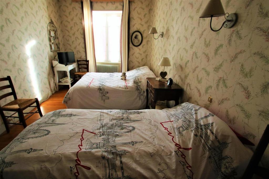 a bedroom with two beds and a bedspread with a drawing on it at La Maison des Chats in Saint-Mary-le-Plain