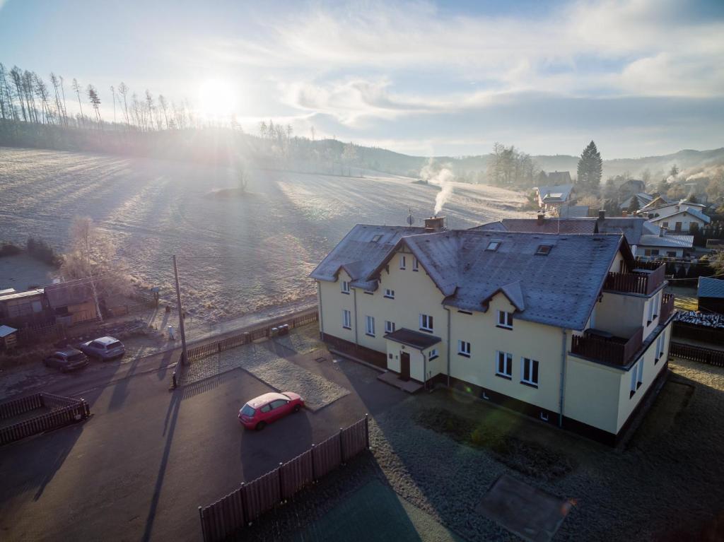 Biały dom z czerwonym samochodem na polu w obiekcie Apartmán Jasmína v Jeseníkách w mieście Karlovice